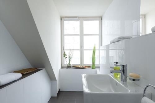 a white bathroom with a sink and a window at BATU Apart Hotel in Munich