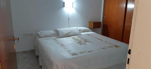 um quarto com uma cama com um edredão branco em APART IMPERIO 1 em Río Cuarto