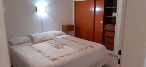 1 dormitorio con cama blanca y armario de madera en APART IMPERIO 1 en Río Cuarto