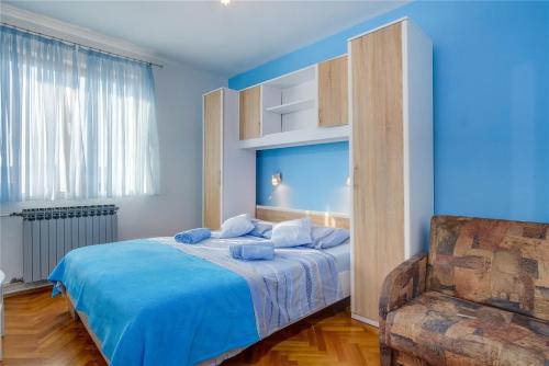 a blue bedroom with a bed and a chair at Apartments with a parking space Losinj, Losinj - 20184 in Mali Lošinj