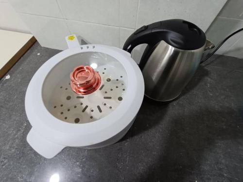 eine weiße Schüssel mit einer roten Kerze darin neben einem Topf in der Unterkunft Cozy 3 Bedroom Apartment Bandar Perda BM in Bukit Mertajam