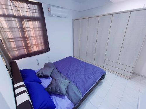 Schlafzimmer mit einem Bett mit blauer Bettwäsche und einem Fenster in der Unterkunft Cozy 3 Bedroom Apartment Bandar Perda BM in Bukit Mertajam