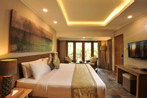 a hotel room with a large bed and a television at Puri Raja Hotel in Legian