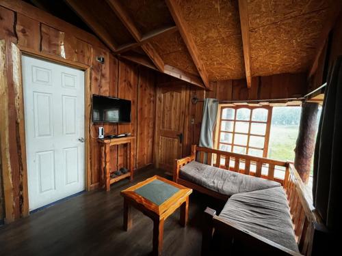 a room with a bed and a door and a table at Cabañas Llakolen in Neltume