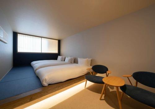 a bedroom with a bed and chairs and a window at HOTEL WOOD TAKAYAMA in Takayama