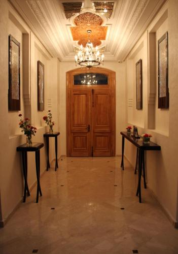 a hallway with a wooden door and two tables with flowers at Dar Souran in Tangier