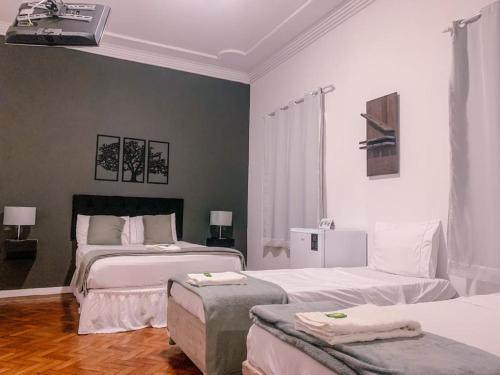 a bedroom with two beds and two ottomans at Pousada Vale Valparaíso Inn- Polo gastronômico in Petrópolis