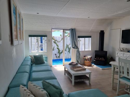 - un salon avec un canapé bleu et une table dans l'établissement Mosselbank Beach Retreat 3, à Paternoster