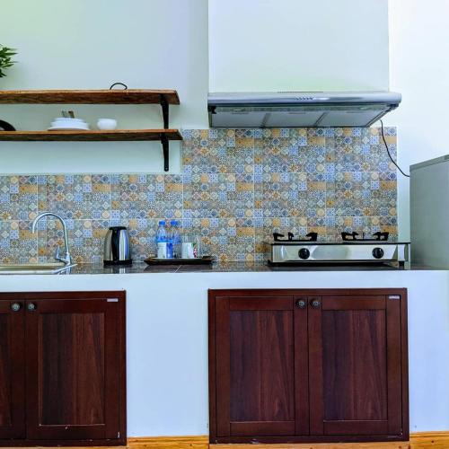 a kitchen with wooden cabinets and a stove at Sanssouci Kep in Kep