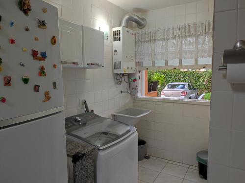 una pequeña cocina con fregadero y lavadora en Apartamento Vivendas do Eucalipto, en Petrópolis