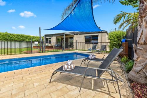 a swimming pool with two chairs next to a house at A Rye Retreat - An Entertainers Delight in Rye