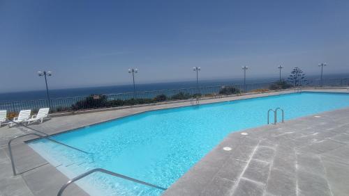 a large swimming pool with a view of the ocean at Reservas altos de huayquique in Iquique