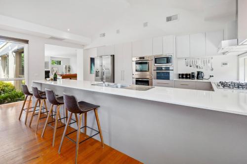 a kitchen with white counters and bar stools at A Rye Retreat - An Entertainers Delight in Rye