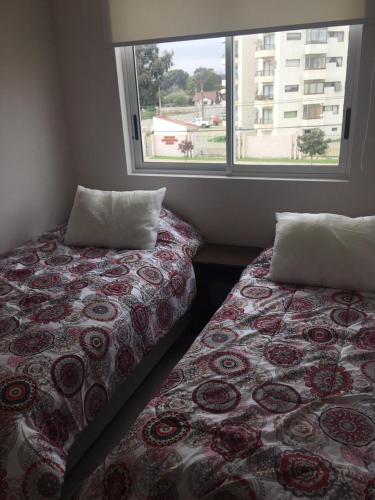two beds in a room with a window at DEPARTAMENTO EN LA SERENA A PASOS DE LA PLAYA in La Serena