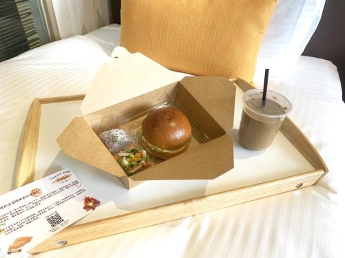 una caja con un sándwich y una bebida en la cama en Treeart Hotel en Taichung