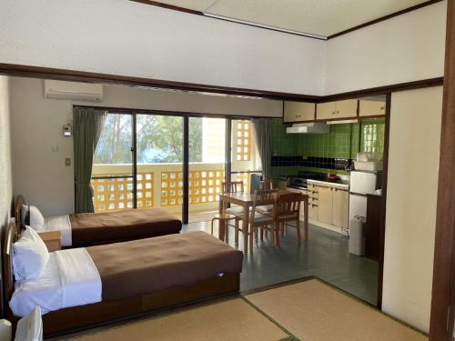 1 dormitorio con 2 camas y cocina con mesa en Hotel & Restaurant On the Beach Lue, en Motobu