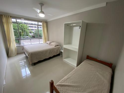 1 dormitorio con 2 camas, espejo y ventana en Apartamento frente mar Gonzaga Santos, en Santos