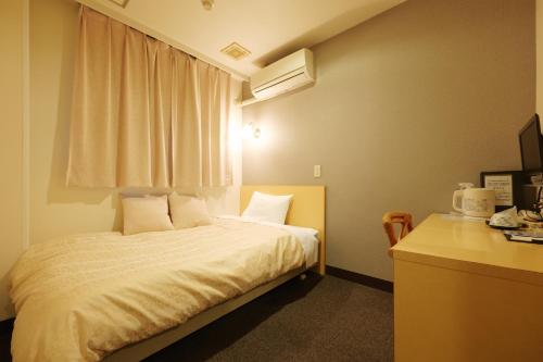 a bedroom with a bed and a desk and a window at Hotel Suntargas Ueno in Tokyo