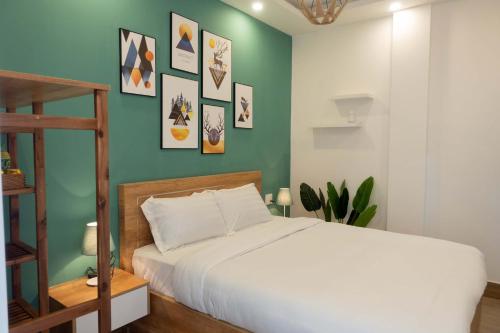 - une chambre avec un lit blanc et un mur vert dans l'établissement Dalat Blanc Hotel 2, à Khu Chi Lăng