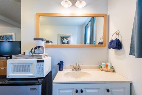 a kitchen with a sink and a microwave and a mirror at Gannett Peak Lodge in Pinedale