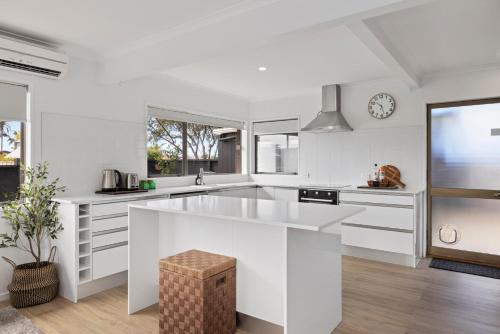 a white kitchen with a large island in the middle at Waitui Wonder - A Comfortable Escape in Mount Maunganui