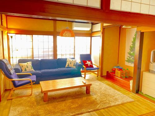 a living room with a blue couch and a coffee table at Ishimaru House in Seki