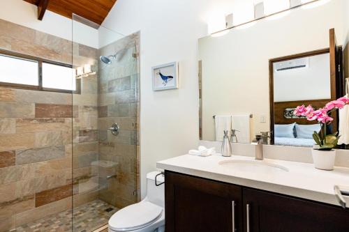 y baño con aseo, lavabo y ducha. en Flamingo Estates 18- 4 BR House with Pool en Brasilito