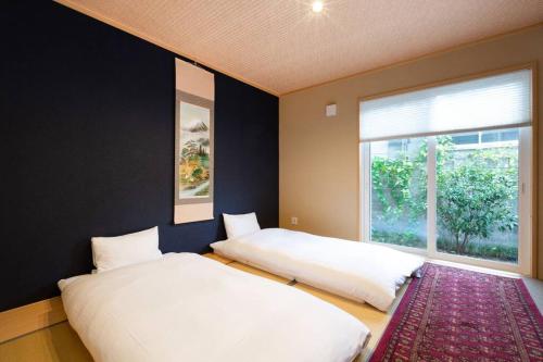 two beds in a room with a window at Kyoto Lanlan Villa in Kyoto