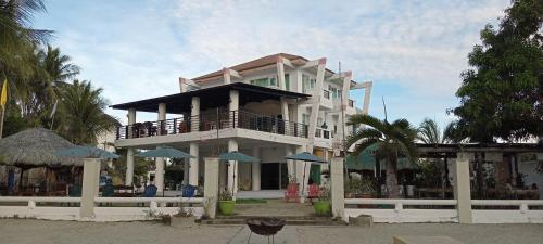 a large white building with blue chairs and umbrellas at North Shores Inn in Currimao