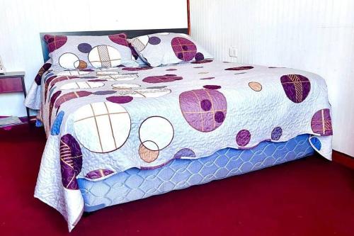ein Bett mit einer Bettdecke und Kissen darauf in der Unterkunft Acogedor departamento interior, a minutos del Lago in Llanquihue