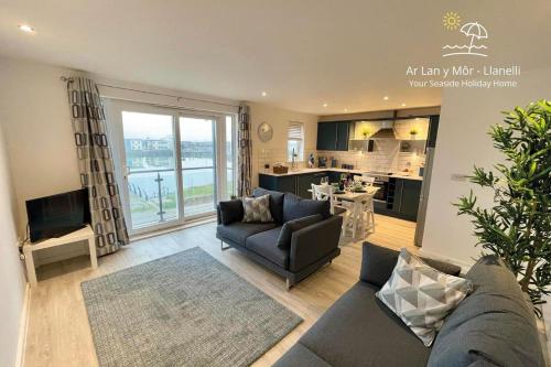 a living room with a couch and a kitchen at Ar Lan Y Mor - Stunning 2 bed coastal apartment in Llanelli