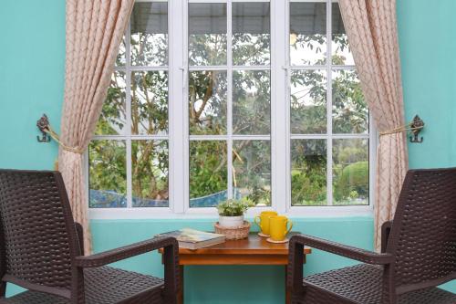 a table with two chairs in front of a window at Gregory House Hostel in Nuwara Eliya