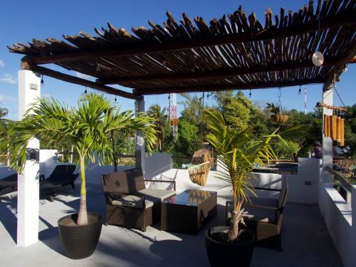 a patio with palm trees and chairs under a pergola at Casa OM in El Cuyo