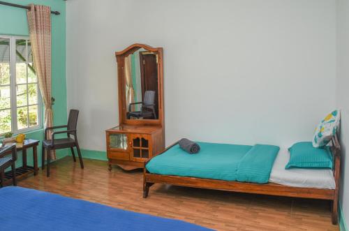 a bedroom with a bed and a mirror and a table at Gregory House Hostel in Nuwara Eliya