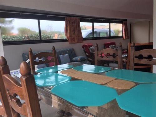 une salle à manger avec une table et des chaises bleues dans l'établissement Pavillon lumineux 3 pièces avec piscine - 6 couchages, proche mer et commerces, parking privé - FR-1-229-818, à Gruissan