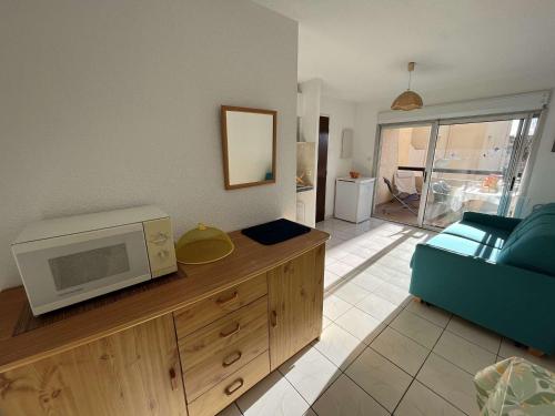 - un salon avec un four micro-ondes et un canapé dans l'établissement Appartement 2 pièces avec piscine, parking, proche commerces - Marseillan - FR-1-387-188, à Marseillan