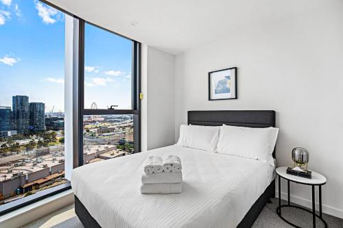 a bedroom with a white bed and a large window at Lumina Suites in Melbourne