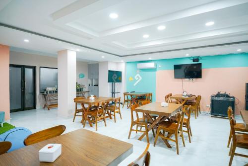 a restaurant with tables and chairs and a flat screen tv at Sans Bougenville Lampung in Lampung
