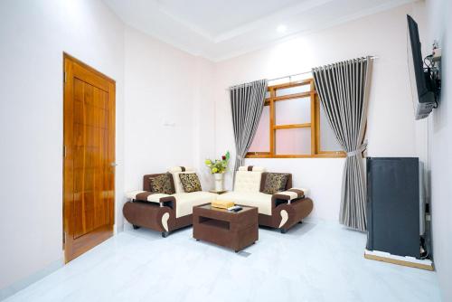 a living room with two couches and a television at Sans Bougenville Lampung in Lampung