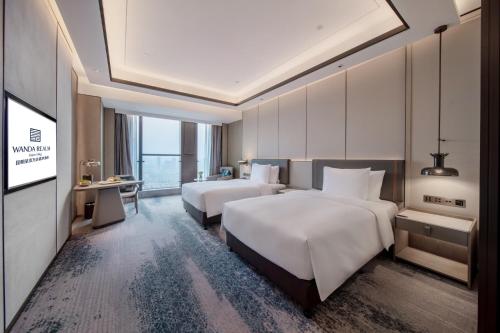 a hotel room with two beds and a television at Wanda Realm Kunming in Kunming