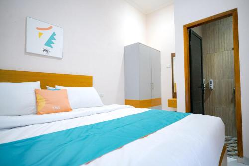 a bedroom with a large bed with colorful pillows at Sans Bougenville Lampung in Lampung