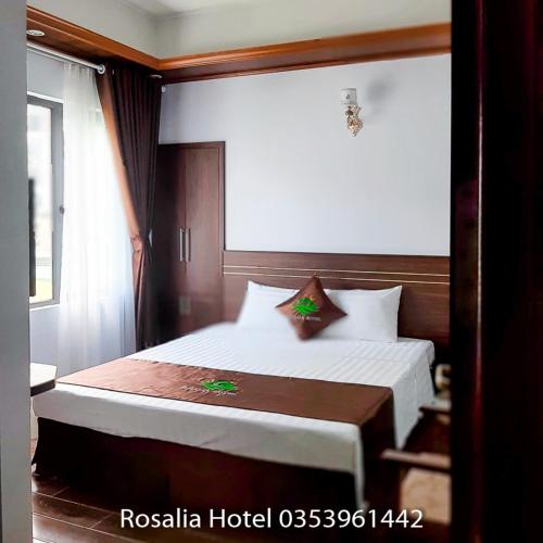 a hotel room with a bed with white sheets at Rosalia Hotel Tam Đảo in Tam Ðảo