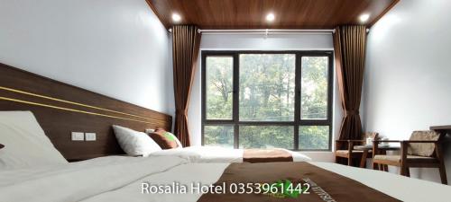 a bedroom with two beds and a large window at Rosalia Hotel Tam Đảo in Tam Ðảo