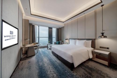 a hotel room with a large bed and a desk at Wanda Realm Kunming in Kunming