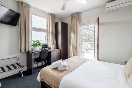 um quarto de hotel com uma cama, uma secretária e uma janela em Huskisson Hotel em Huskisson