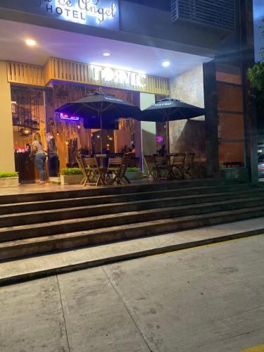 a group of tables and umbrellas outside of a hotel at Apartahotel Plaza de ángel 74 in Barranquilla