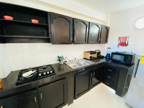 a kitchen with black cabinets and a sink and a microwave at Apartamentos Sweet Island in San Andrés