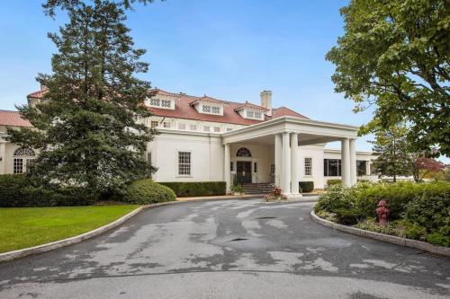 uma grande casa branca com uma árvore e uma entrada em Chevy Chase 4 BR 2 offices Comfortable Inviting em Washington