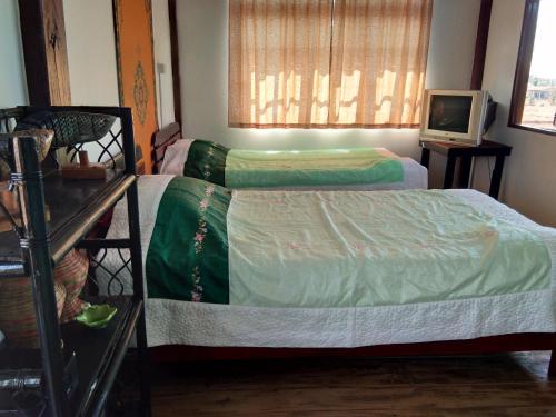 a bedroom with two beds and a tv in it at Lek's Issan Home and Travel in Ban Kut Khaen