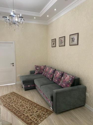 salon z zieloną kanapą i żyrandolem w obiekcie 3х комнатная квартира жк Арай w mieście Ałma-Ata